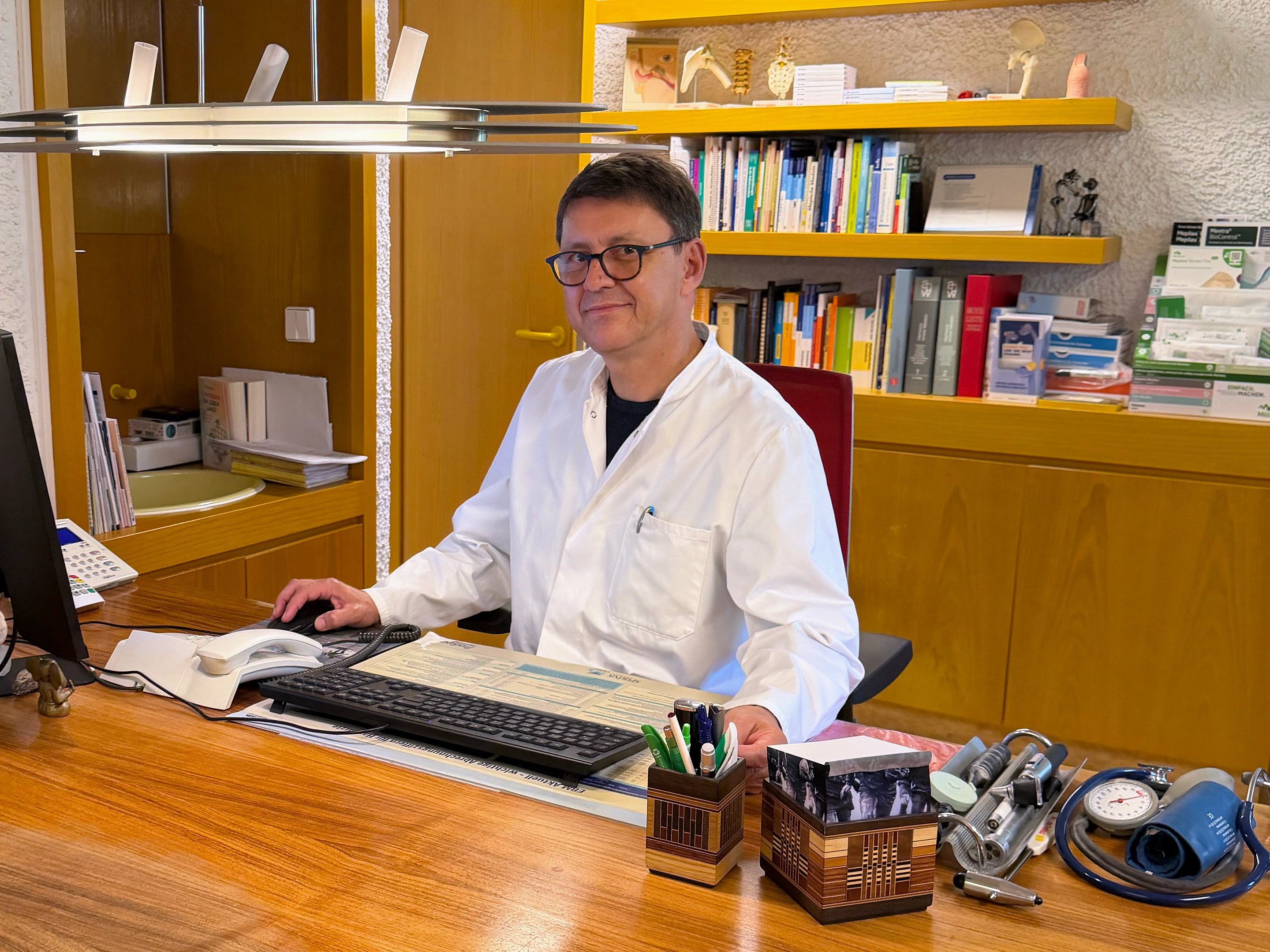 Dr. Kunz an seinem Arbeitsplatz im Sprechzimmer.